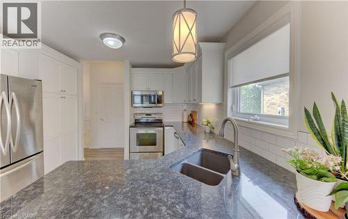 Kitchen featuring dark granite countertops, white cabinetry, stainless steel appliances, and a double basin sink with a gooseneck faucet - 249 Dearborn Boulevard, Waterloo, ON - Indoor Photo Showing Kitchen With Double Sink With Upgraded Kitchen
