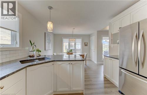 Kitchen featuring white cabinetry, dark stone countertops, stainless steel appliances, and wood-finish flooring - 249 Dearborn Boulevard, Waterloo, ON - Indoor Photo Showing Kitchen With Double Sink