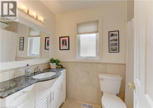 Bathroom featuring a single vanity with a dark speckled countertop, an oval undermount sink, and white louvered cabinetry - 249 Dearborn Boulevard, Waterloo, ON - Indoor Photo Showing Bathroom