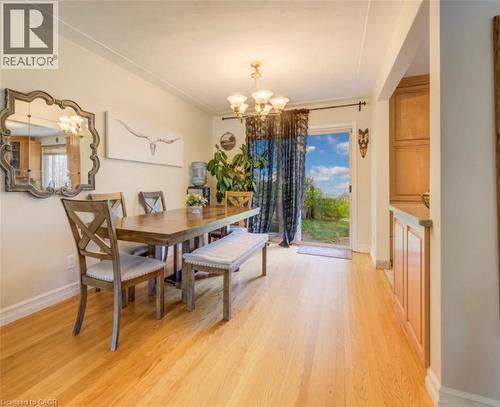 Dining area featuring wood-finish flooring, a contemporary chandelier, and direct outdoor access through a glass door - 209 Willowdale Avenue Unit# Upper, Waterloo, ON - Indoor Photo Showing Dining Room