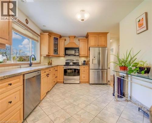 Kitchen featuring light wood cabinetry, stainless steel appliances, a tile backsplash, and a large window above the sink - 209 Willowdale Avenue Unit# Upper, Waterloo, ON - Indoor Photo Showing Kitchen