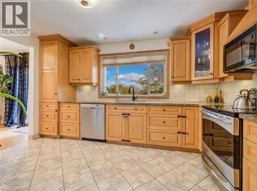 Kitchen featuring light wood cabinetry with varied storage options, stainless steel appliances including a dishwasher and range, granite-look countertops, and a tiled backsplash - 209 Willowdale Avenue Unit# Upper, Waterloo, ON - Indoor Photo Showing Kitchen