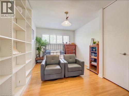 Bright room featuring wood-finish flooring, a full-height built-in shelving unit, white walls, and a window with plantation shutters - 209 Willowdale Avenue Unit# Upper, Waterloo, ON - Indoor