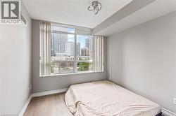 Bedroom featuring multiple windows, wood finished floors, and a view of city - 