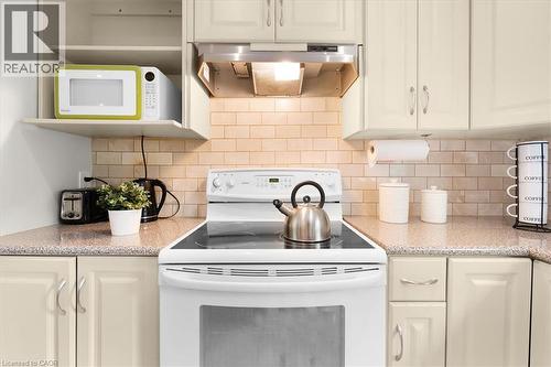Kitchen featuring a white electric range with a coordinating range hood, light-toned cabinetry, light-colored subway tile backsplash, and speckled countertops - 421 Bairstow Crescent, Waterloo, ON - Indoor Photo Showing Kitchen