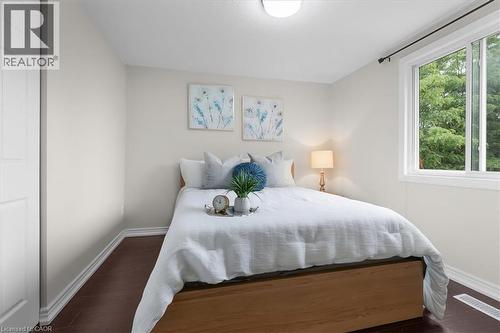 Bedroom featuring a sliding window, dark wood-finish flooring, white baseboards, a flush-mount ceiling light, and a paneled interior door - 421 Bairstow Crescent, Waterloo, ON - Indoor Photo Showing Bedroom