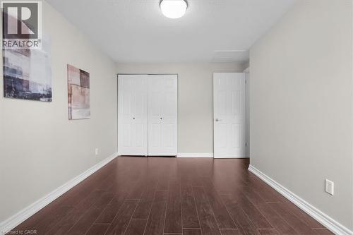 Hardwood-finish flooring complements light-toned walls and white trim - 421 Bairstow Crescent, Waterloo, ON - Indoor Photo Showing Other Room