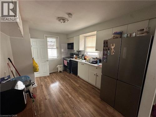 Kitchen featuring wood-finish flooring, white cabinetry, and a modern ceiling light fixture - 240 West 2Nd Street, Hamilton, ON - Indoor
