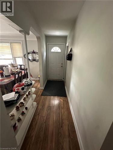 Entryway featuring wood-finish flooring, a white paneled door with a half-round transom window, and an arched doorway leading to an interior space - 240 West 2Nd Street, Hamilton, ON - Indoor Photo Showing Other Room