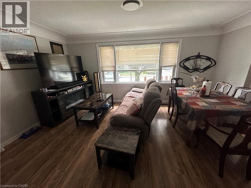Open-concept living and dining area featuring wood-finish flooring, a broad window with blinds, and a ceiling-mounted light fixture - 240 West 2Nd Street, Hamilton, ON - Indoor Photo Showing Other Room
