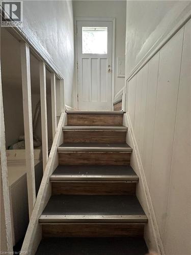 Staircase featuring wood-finish treads with carpet inserts, metal nosings, and painted balusters - 240 West 2Nd Street, Hamilton, ON - Indoor Photo Showing Other Room