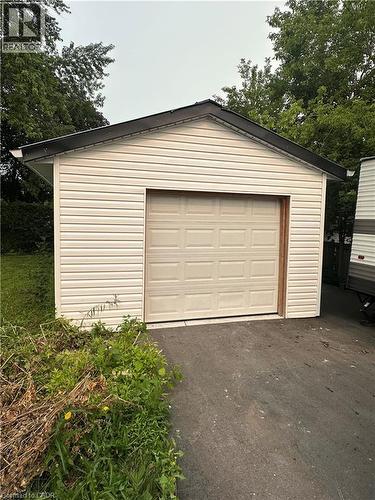 Detached garage featuring light-colored horizontal siding, a gabled roofline with dark shingles, and a paneled garage door - 240 West 2Nd Street, Hamilton, ON - Outdoor