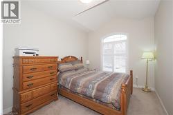 Vaulted ceiling bedroom with arched window featuring white shutters - 