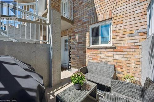 Private patio area featuring brick exterior, white framed window, and concrete privacy wall - 50 Howe Drive Unit# 9D, Kitchener, ON - Outdoor With Exterior
