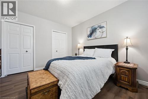 Bedroom featuring wood-finish flooring, light grey walls, and two bi-fold closet doors - 50 Howe Drive Unit# 9D, Kitchener, ON - Indoor Photo Showing Bedroom