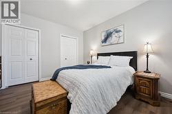 Bedroom featuring wood-finish flooring, light grey walls, and two bi-fold closet doors - 