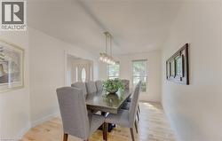 Dedicated dining area featuring wood-finish flooring, light-toned walls, and a linear pendant light fixture - 