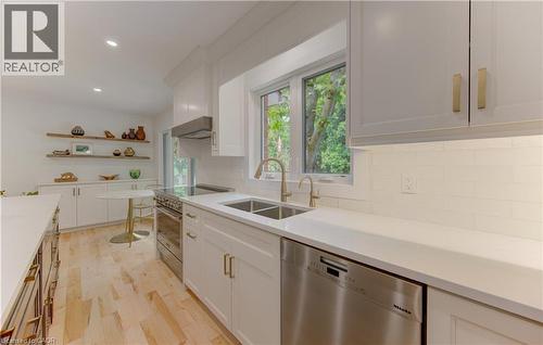 Contemporary kitchen featuring light wood-finish flooring, white cabinetry with gold-tone hardware, and white countertops - 307 Grand River Boulevard, Kitchener, ON - Indoor Photo Showing Kitchen With Double Sink