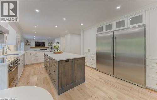 Spacious kitchen featuring a large central island with storage, stainless steel appliances, light wood-finish flooring, white cabinetry, and recessed lighting - 307 Grand River Boulevard, Kitchener, ON - Indoor Photo Showing Kitchen With Upgraded Kitchen