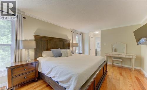 Spacious sleeping area featuring warm-toned wood-finish flooring, a large window with natural light, crown molding, and a neutral wall color - 307 Grand River Boulevard, Kitchener, ON - Indoor Photo Showing Bedroom