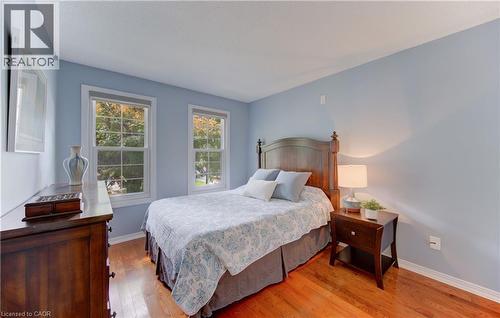Room featuring wood-finish flooring, light blue walls, white baseboards, and two double-hung windows with white trim - 307 Grand River Boulevard, Kitchener, ON - Indoor Photo Showing Bedroom