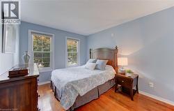 Room featuring wood-finish flooring, light blue walls, white baseboards, and two double-hung windows with white trim - 