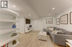 Open-concept living space featuring light wood-finish flooring, recessed ceiling lighting, a built-in media console, and a white paneled door - 