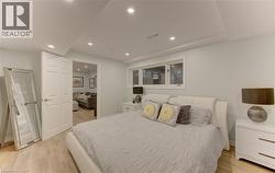 Bedroom featuring contemporary wood-finish flooring, recessed lighting, and a white six-panel door - 