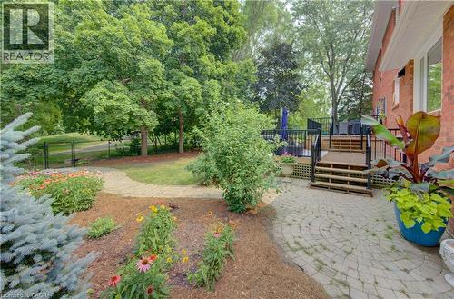 Expansive backyard featuring a circular paver patio, multi-level wooden deck with dark railings, and a brick exterior - 307 Grand River Boulevard, Kitchener, ON - Outdoor