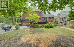Expansive backyard featuring a multi-level deck with black railings, a large patio area, mature trees, and a winding stone pathway - 
