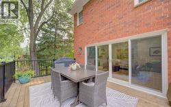 Expansive outdoor deck featuring wood flooring, black metal railings, and a brick exterior - 