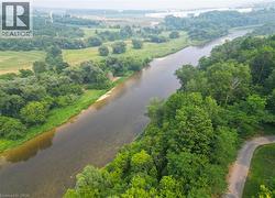 Riverfront property featuring extensive tree coverage, a natural riverbed, and a paved road bordering the perimeter - 