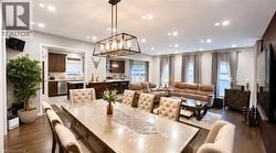 Open-concept living space featuring wood-finish flooring, recessed lighting, and a linear chandelier - 