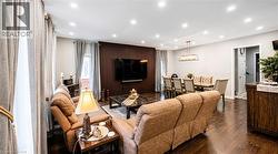 Open-concept living and dining area featuring dark wood-finish flooring, recessed ceiling lighting, and a dark wood accent wall - 