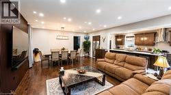 Spacious open-concept living area featuring wood-finish flooring, recessed lighting, and a kitchen with dark wood cabinetry - 