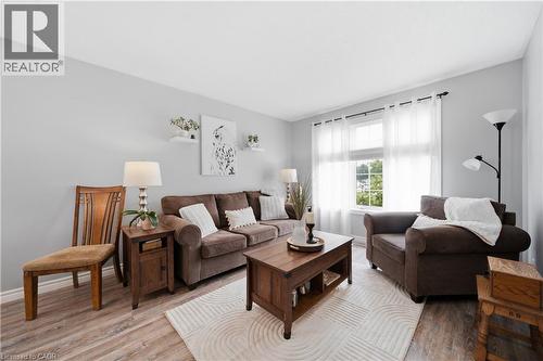 Spacious living area featuring wood-finish flooring, light gray walls, a large window with sheer white curtains, and recessed ceiling lighting - 79 Beaverbrook Crescent, Cambridge, ON - Indoor Photo Showing Living Room