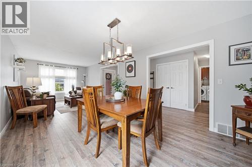 Dining area featuring a contemporary linear chandelier, wood-finish flooring, and light gray wall paint - 79 Beaverbrook Crescent, Cambridge, ON - Indoor Photo Showing Dining Room