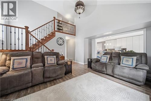 Vaulted ceiling living area featuring wood-finish flooring, a contemporary ceiling fan, and a wood staircase with black iron spindles - 79 Beaverbrook Crescent, Cambridge, ON - Indoor Photo Showing Other Room