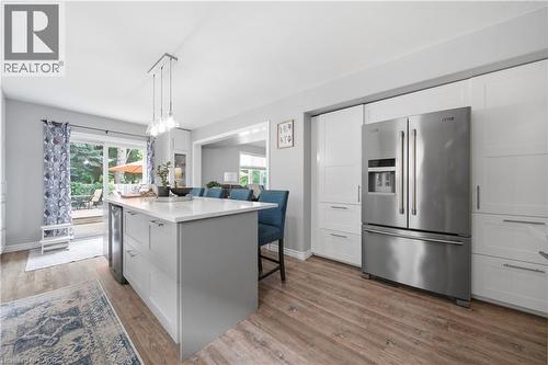 Modern kitchen featuring an expansive center island with seating, a built-in beverage cooler, and pendant lighting - 79 Beaverbrook Crescent, Cambridge, ON - Indoor Photo Showing Kitchen