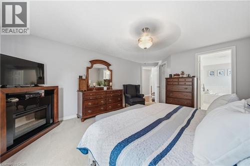 Carpeted bedroom featuring a built-in electric fireplace and a ceiling-mounted fixture - 79 Beaverbrook Crescent, Cambridge, ON - Indoor Photo Showing Bedroom