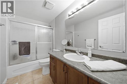 Bathroom featuring a wood-finish vanity with an integrated sink, a large mirror, and a shower-tub combination with sliding frosted glass doors - 79 Beaverbrook Crescent, Cambridge, ON - Indoor Photo Showing Bathroom