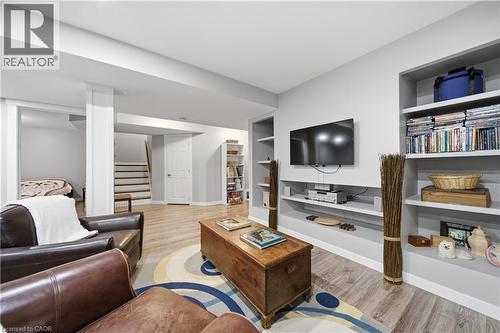 Spacious living area featuring light wood-finish flooring, built-in shelving, a dedicated media wall, and a separate stairway access - 79 Beaverbrook Crescent, Cambridge, ON - Indoor Photo Showing Living Room