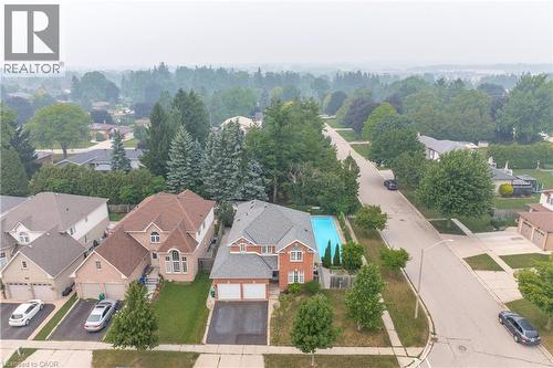 Brick exterior residence featuring an in-ground swimming pool, an attached two-car garage, and a paved driveway - 79 Beaverbrook Crescent, Cambridge, ON - Outdoor With View