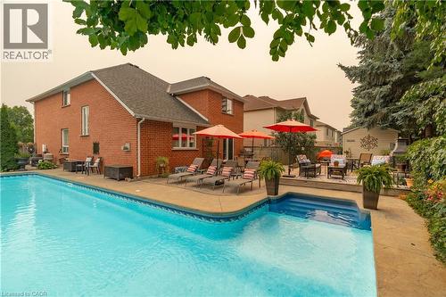 Brick exterior with a large in-ground pool featuring integrated steps and a surrounding concrete patio - 79 Beaverbrook Crescent, Cambridge, ON - Outdoor With In Ground Pool With Deck Patio Veranda
