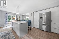 Modern kitchen featuring an expansive center island with seating, a built-in beverage cooler, and pendant lighting - 