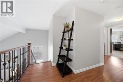 Upper landing featuring wood-finish flooring, a wrought iron and wood balustrade, and a recessed ceiling light - 