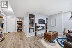 Recreational area featuring wood-finish flooring, recessed lighting, and a built-in media center with shelving - 