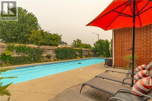 Backyard featuring an in-ground swimming pool with a concrete surround, wood privacy fencing, and a brick exterior wall - 79 Beaverbrook Crescent, Cambridge, ON - Outdoor With In Ground Pool