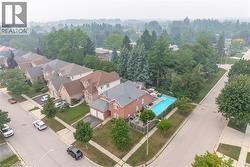 Brick two-story residence featuring a gray shingled roof and an attached two-car garage - 