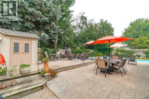Expansive stamped concrete patio featuring a built-in swimming pool and a dedicated outdoor dining area - 79 Beaverbrook Crescent, Cambridge, ON - Outdoor With Deck Patio Veranda